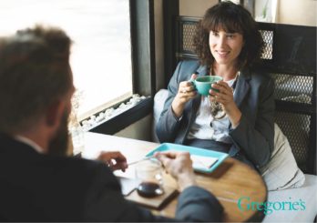 Man and a woman sitting at a table drinking coffee.