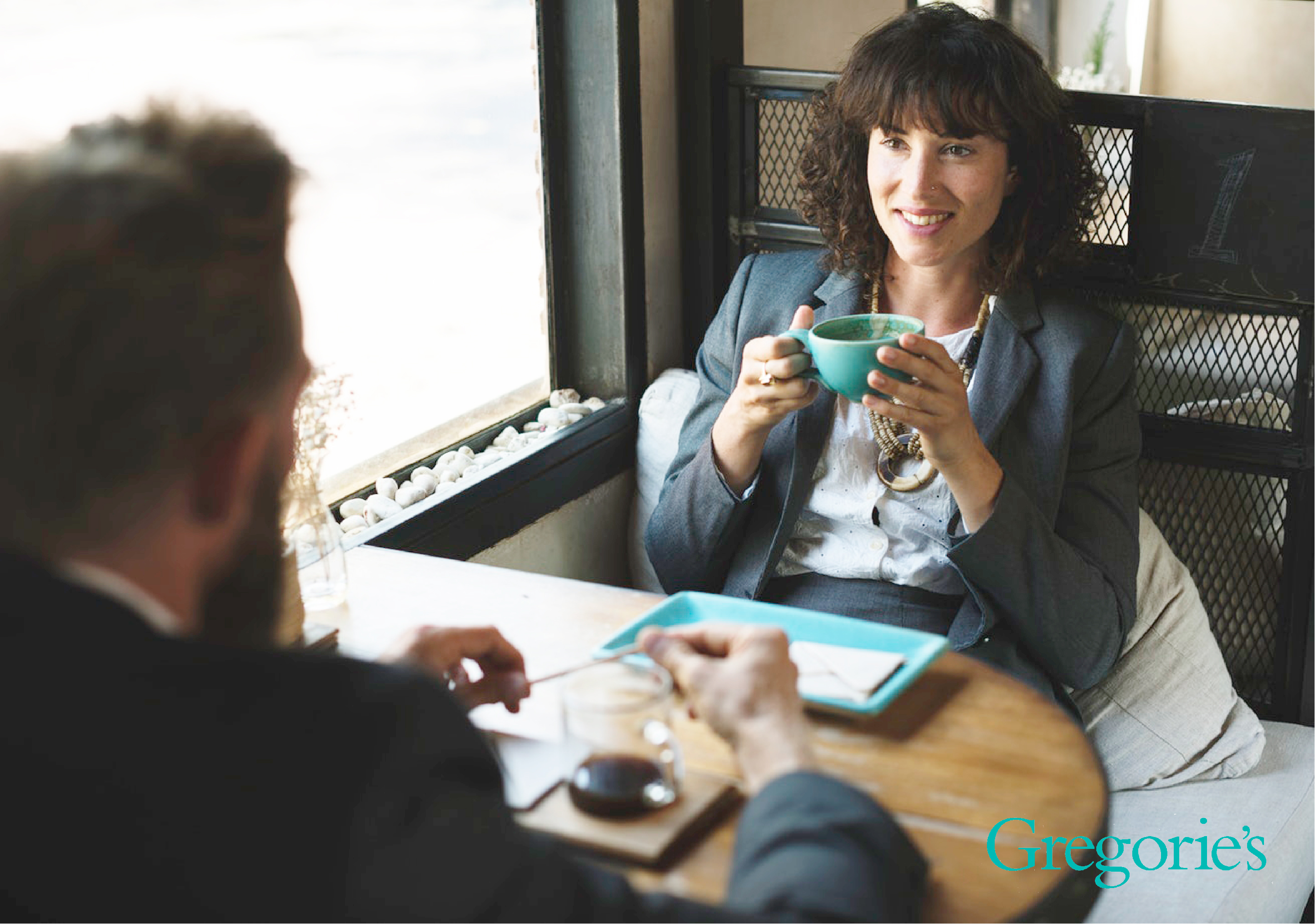 Man and a woman sitting at a table drinking coffee.